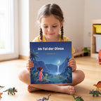 Maedchen haelt zwischen Spielzeugdinos das personalisierte Kinderbuch Im Tal der Dinos