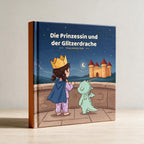 Hardcover Die Prinzessin und der Glitzerdrache an eine helle Wand gelehnt, oranger Buchruecken sichtbar